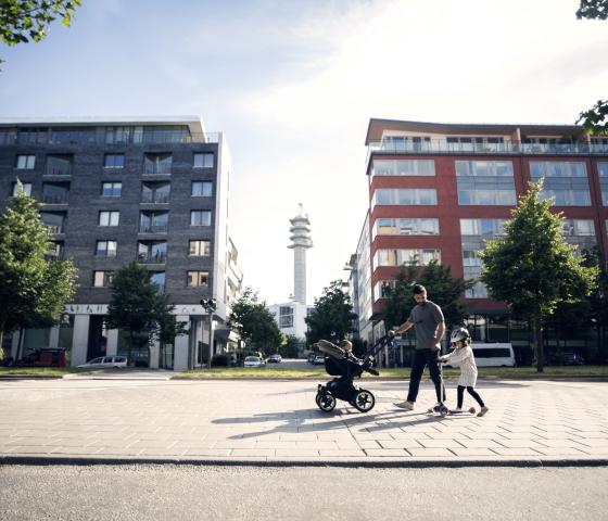 A man walking in a city with a stroller and a child